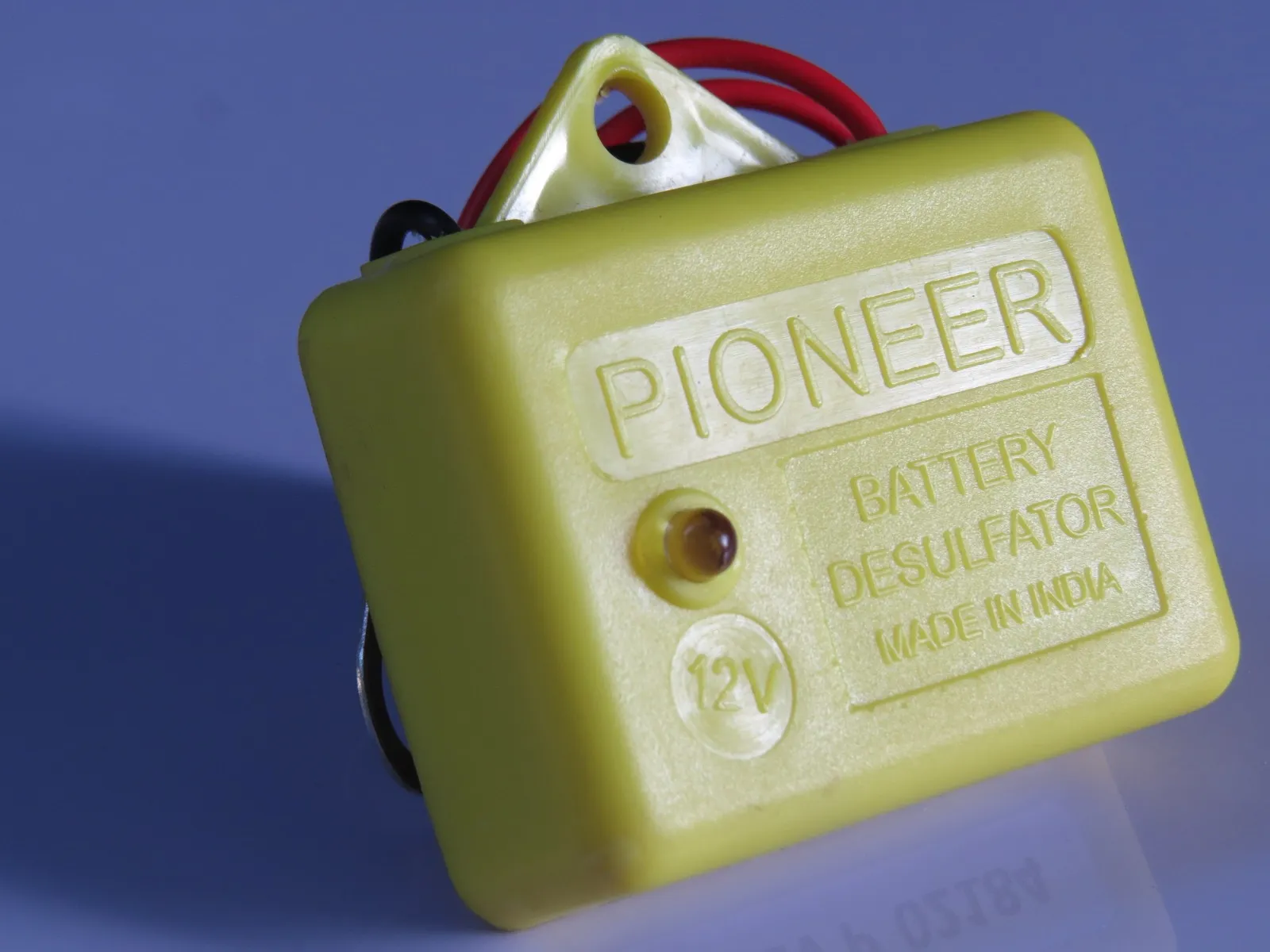 Close-up of the yellow Pioneer 12 V battery desulfator, its case moulded with the words Pioneer, Battery Desulfator, Made in India