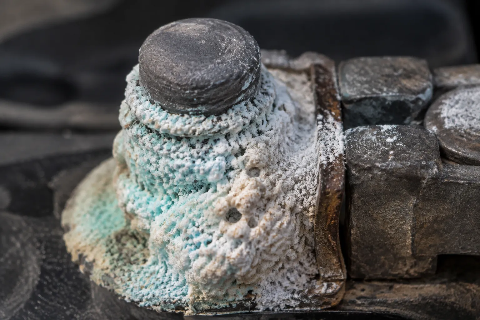 Close-up of a battery terminal crusted with pale blue-green sulphate deposits